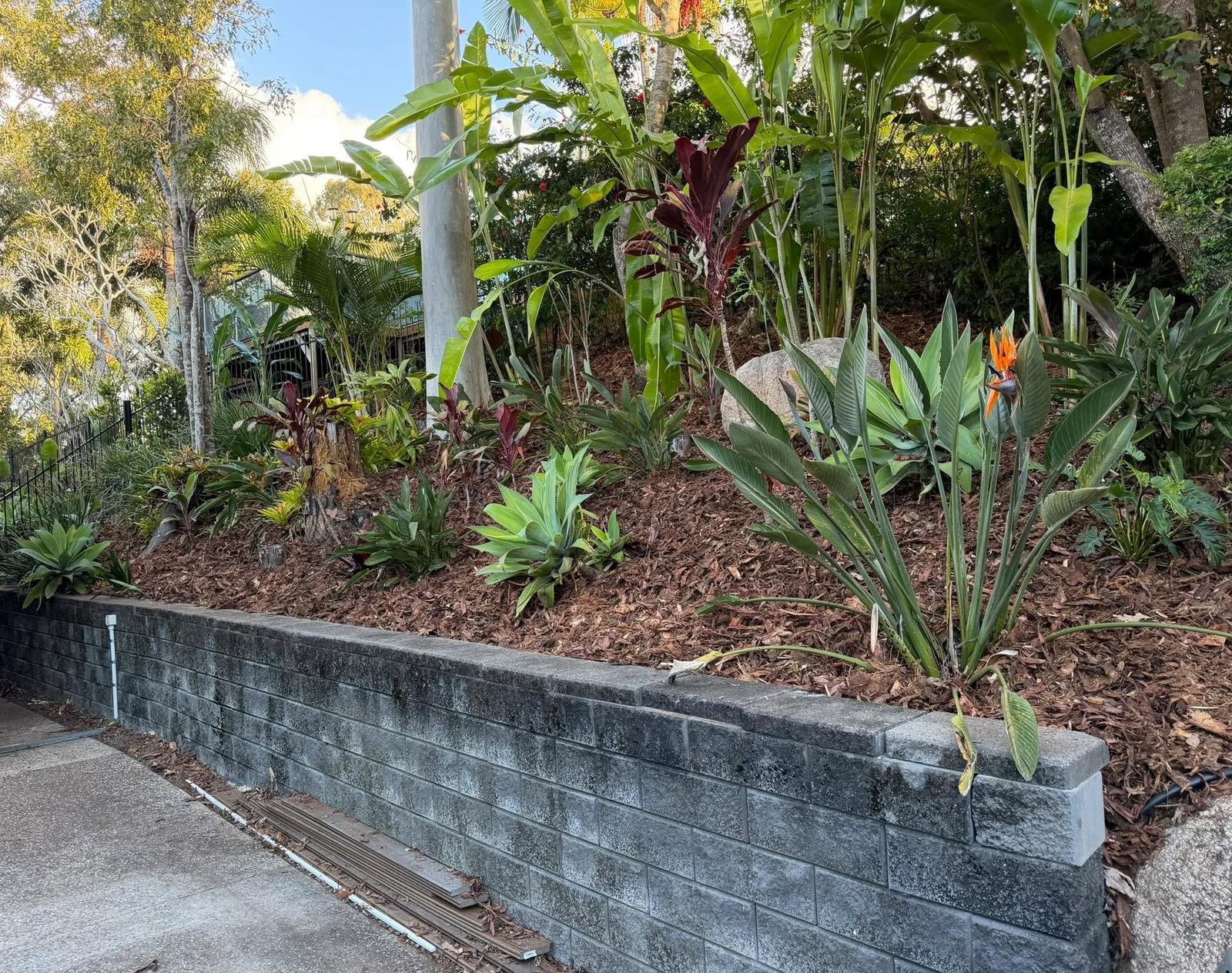 Block retaining wall with fresh mulch and tropical planting