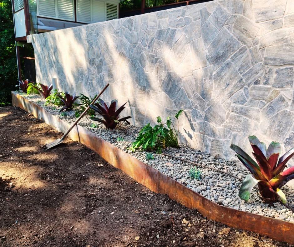 Bromeliad garden bed with pebbles and steel edging